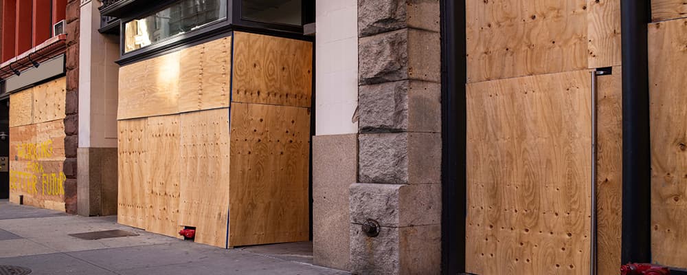 Storefront windows boarded up after emergency damage